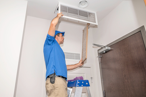 Technician on a ladder replacing a dirty air filter