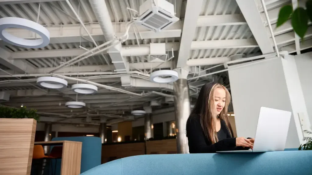 woman working in a commercial building with air ducts seen above the ceiling